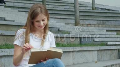 公园里年轻漂亮的女孩<strong>正在看书</strong>。 一个学生<strong>正在</strong>学习一本书，翻页。 混凝土上的裂缝